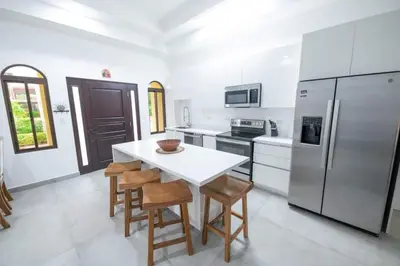 a white kitchen with a white table and chairs at Villa Alegría de vivir by Vacation Pura Vida in Bejuco