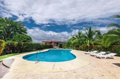 a swimming pool with chairs and a house at Villa Camino Corral by Vacation Pura Vida in Esterillos