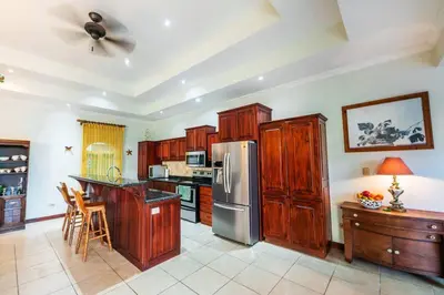 a kitchen with wooden cabinets and a stainless steel refrigerator at Villa Encanto by Vacation Pura Vida in Bejuco