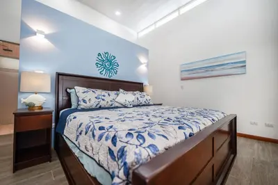 a bedroom with a bed with a blue and white comforter at Villa Luna Nueva by Vacation Pura Vida in Esterillos