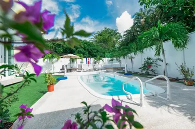 a swimming pool in a yard with purple flowers at Villa Luna Nueva by Vacation Pura Vida in Esterillos
