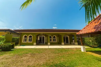 a green house with a palm tree in front of it at Villa San Miguel by Vacation Pura Vida in Bejuco