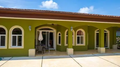 a green house with a patio and a table at Villa San Miguel by Vacation Pura Vida in Bejuco
