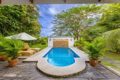 a swimming pool in a backyard with trees and plants at Villa Tenga Paz by Vacation Pura Vida in Esterillos
