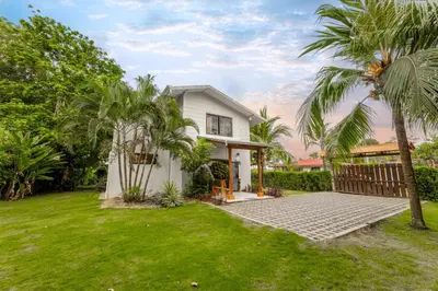 a white house with palm trees in the yard at Villa Tenga Paz by Vacation Pura Vida in Esterillos