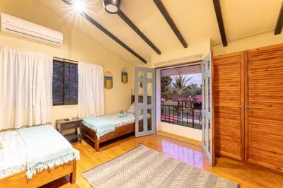 a bedroom with two beds and a balcony at Villa Tenga Paz by Vacation Pura Vida in Esterillos