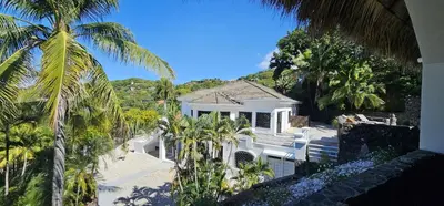 a white house with palm trees in front of it at Villa Pura Vida - All Inclusive in Ocotal