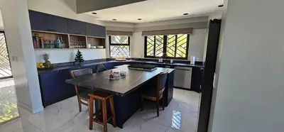 a kitchen with blue cabinets and a table with chairs at Villa Pura Vida - All Inclusive in Ocotal