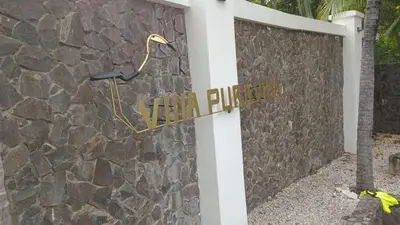 a building with a stone wall with a sign on it at Villa Pura Vida - All Inclusive in Ocotal