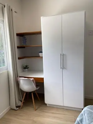 a white cabinet in a room with a desk and a chair at Casa Arribada- Bright 4Br House 5-min walk to Beach, Pool, BBQ in Playa Flamingo