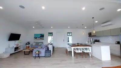 a living room and kitchen with a couch and a table at Casa Arribada- Bright 4Br House 5-min walk to Beach, Pool, BBQ in Playa Flamingo
