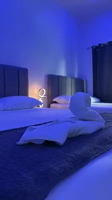 two beds in a room with blue lighting at H et L in Tortuguero