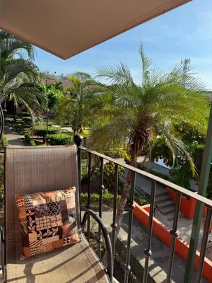 a balcony with a chair and palm trees at Happy Oasis Second Floor Condo with Terrace in Coco