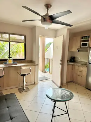 a living room with a ceiling fan and a kitchen at Sandy Shore Two bedroom condo across beach in Coco