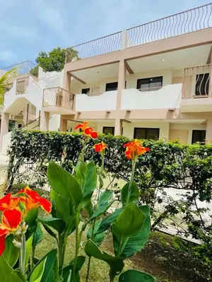 a building with red flowers in front of it at Sandy Shore Two bedroom condo across beach in Coco