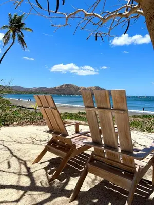 a wooden chair sitting on a beach near the ocean at Sandy Shore Two bedroom condo across beach in Coco