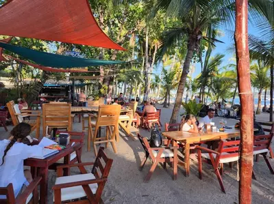 a group of people sitting at tables on the beach at SamaraLofts near town and beaches in Sámara