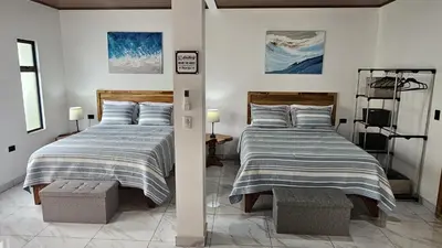 two beds in a white room with two beds sidx sidx sidx at Mi casa, tu casa Manuel Antonio, Quepos in Quepos