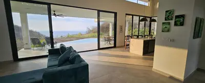 a living room with a couch and large glass doors at El Coco Oasis Where Luxury Meets Nature! in Sardinal
