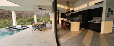 a kitchen and dining room with a table and a pool at El Coco Oasis Where Luxury Meets Nature! in Sardinal