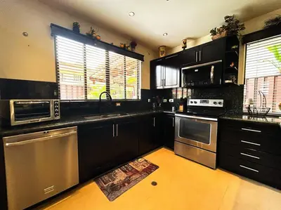 a kitchen with black cabinets and stainless steel appliances at Beautiful Family Villa near Punta Leona in Quebrada Ganado