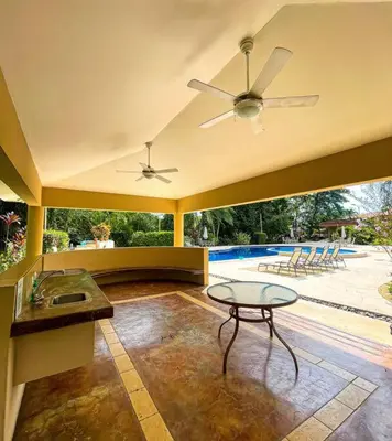 a living room with a ceiling fan and a table at Beautiful Family Villa near Punta Leona in Quebrada Ganado
