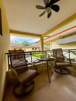 a balcony with two chairs and a table and a ceiling fan at Beautiful Family Villa near Punta Leona in Quebrada Ganado