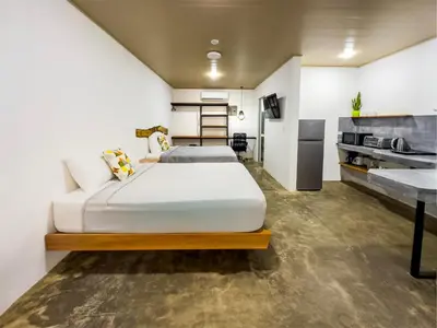 a bedroom with two beds and a kitchen at Nomad Living CR Tárcoles in Tarcoles