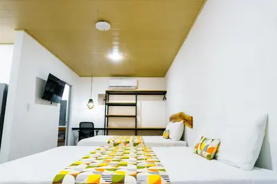 two beds in a small room with a ceiling at Nomad Living CR Tárcoles in Tarcoles