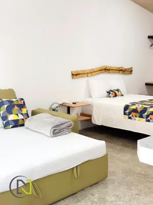 a room with two beds and a table in it at Nomad Living CR Tárcoles in Tarcoles