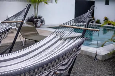 a hammock sitting next to a swimming pool at Nomad Living CR Tárcoles in Tarcoles