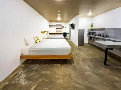 a bedroom with two beds and a desk at Nomad Living CR Tárcoles in Tarcoles