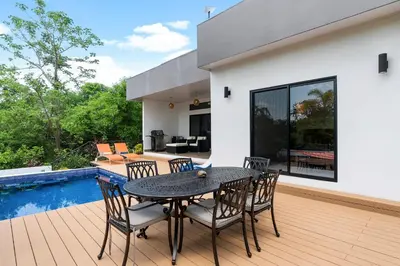 a patio with a table and chairs next to a pool at Villa with Minimalist Design & Scenic Deck with Private Infinity Pool and Jungle Views in Coco