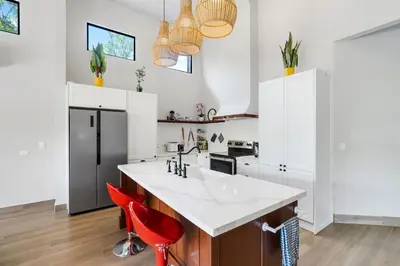a kitchen with a white counter and red chairs at Villa with Minimalist Design & Scenic Deck with Private Infinity Pool and Jungle Views in Coco