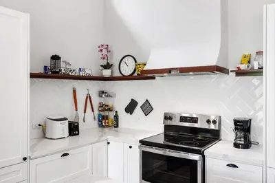 a kitchen with white cabinets and a black stove at Villa with Minimalist Design & Scenic Deck with Private Infinity Pool and Jungle Views in Coco