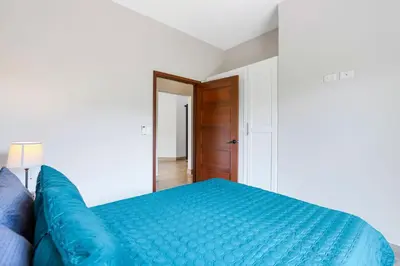 a bedroom with a blue bed and a wooden door at Villa with Minimalist Design & Scenic Deck with Private Infinity Pool and Jungle Views in Coco