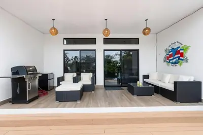 a living room with white furniture and a tv at Villa with Minimalist Design & Scenic Deck with Private Infinity Pool and Jungle Views in Coco