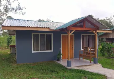 a small blue house with a porch and a bench at Escapadita Pura Vida in Fortuna