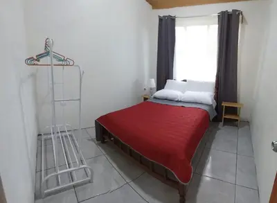 a bedroom with a bed with a red blanket and a window at Escapadita Pura Vida in Fortuna