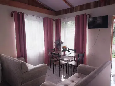 a living room with a table and chairs and a television at Escapadita Pura Vida in Fortuna