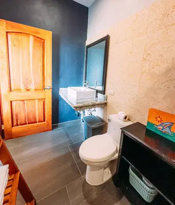 a bathroom with a white toilet and a sink at Tinajas Arenal Lakefront Lodge in Nuevo Arenal