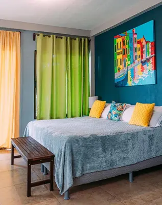 a bedroom with a bed with a painting on the wall at Tinajas Arenal Lakefront Lodge in Nuevo Arenal