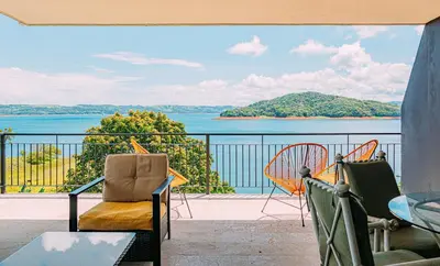a balcony with chairs and a view of the water at Tinajas Arenal Lakefront Lodge in Nuevo Arenal