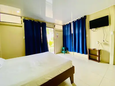 a bedroom with a bed with blue curtains and a television at Cabinas Arenal Home in Tanque