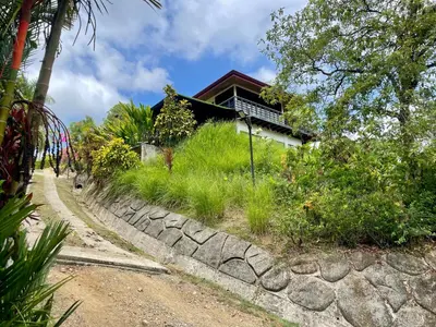 a house with a stone wall next to a road at Villas Pura Vida in Ojochal