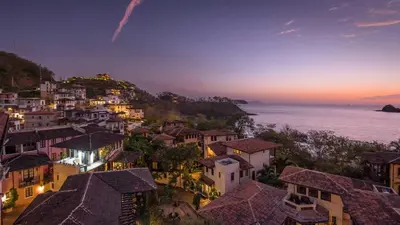 a view of a town at night with the ocean at Las Catalinas Doorway in Playa Flamingo