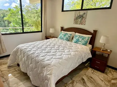 a bedroom with a large bed and two windows at Olas de Oro in Nicoya