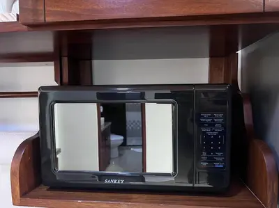 a black microwave sitting in a wooden cabinet at Casita Oropéndola in Monterrey