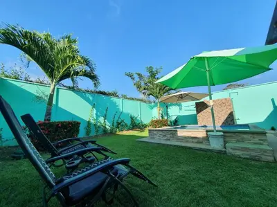 two lawn chairs and an umbrella in a yard at Casa Las Palmas Playa Bejuco in Bejuco