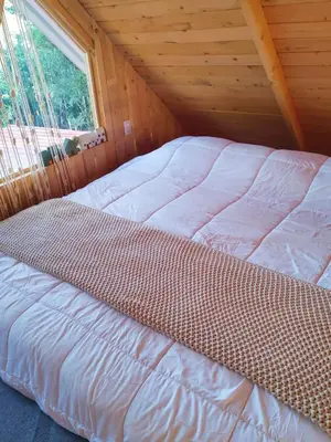 a bed in a wooden cabin with a window at Cabaña Lugar de Paz in División